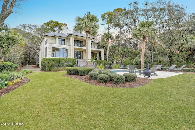 rear view of property with a balcony, a patio, and a lawn