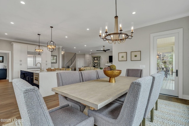 dining space featuring an inviting chandelier, crown molding, sink, and light wood-type flooring