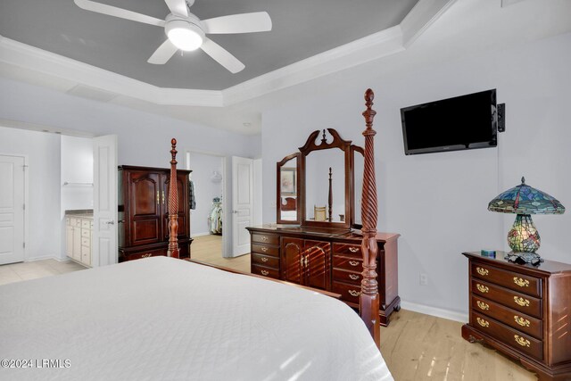 bedroom featuring connected bathroom, light hardwood / wood-style flooring, a raised ceiling, and ceiling fan