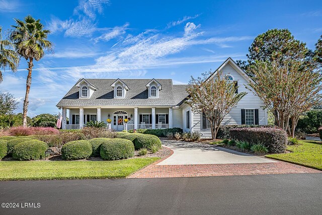 cape cod home featuring a front yard and covered porch