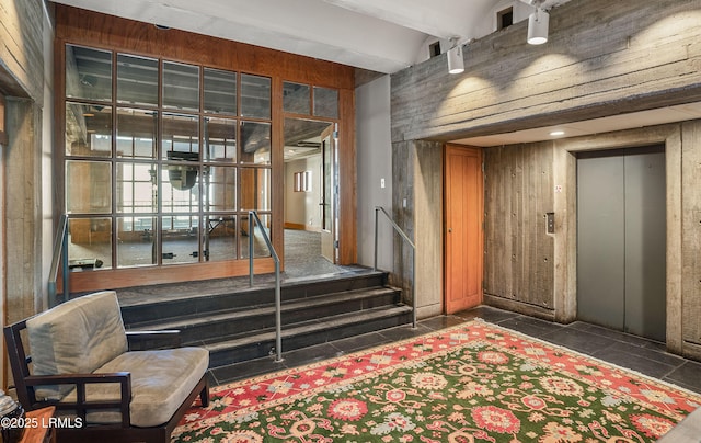 interior space featuring beamed ceiling, elevator, and wooden walls