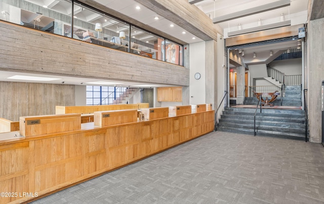 interior space featuring a high ceiling, carpet floors, and wooden walls