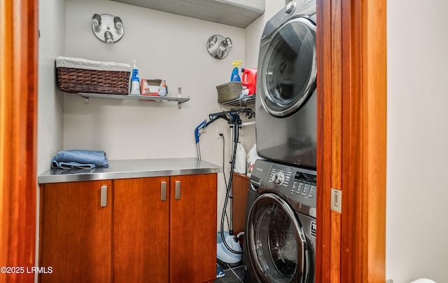 laundry room with cabinets and stacked washer and clothes dryer