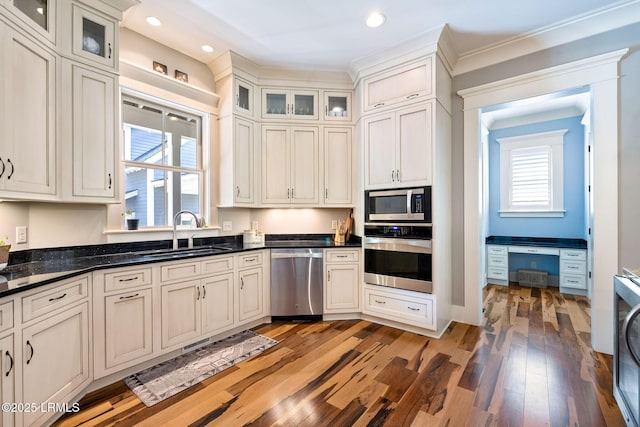 kitchen featuring hardwood / wood-style floors, dark stone countertops, stainless steel appliances, and sink