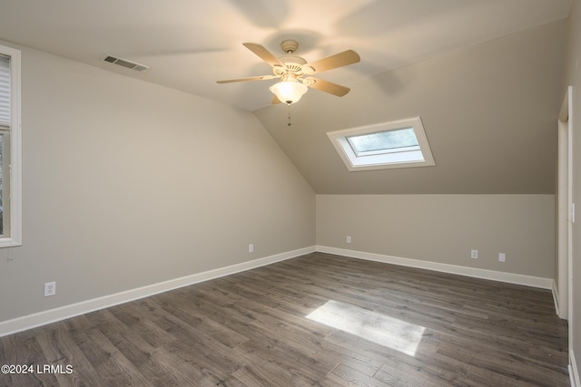 additional living space with dark hardwood / wood-style flooring, ceiling fan, and vaulted ceiling with skylight