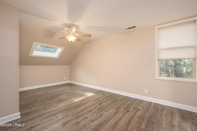 additional living space with dark hardwood / wood-style floors, ceiling fan, and lofted ceiling with skylight