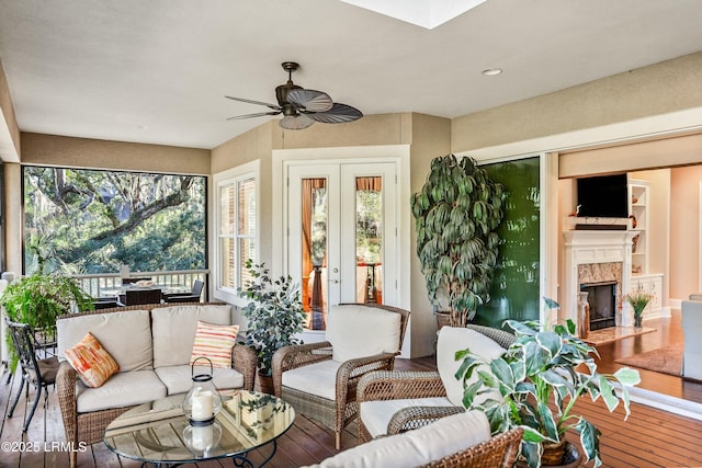 sunroom featuring a ceiling fan and a high end fireplace