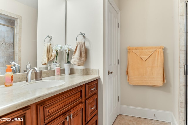 full bath featuring vanity, baseboards, tiled shower, and tile patterned floors