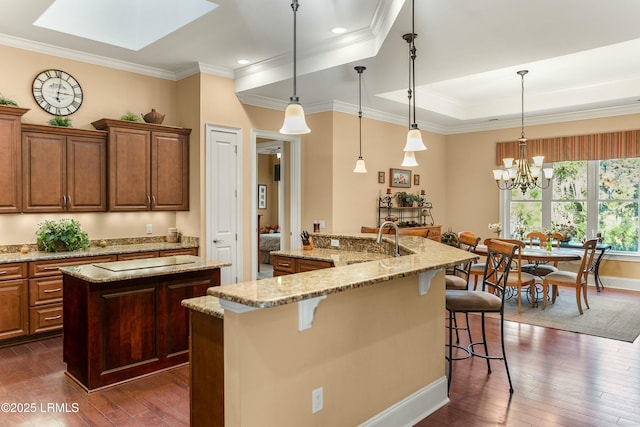 kitchen featuring a large island with sink, pendant lighting, a breakfast bar area, and dark hardwood / wood-style flooring