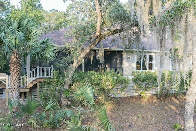 view of front of property featuring a shingled roof and stairway