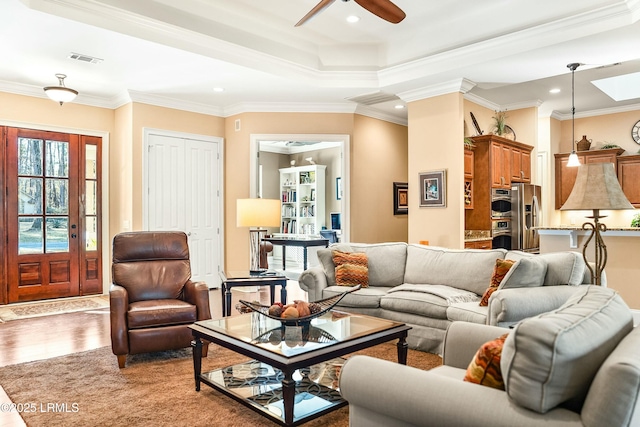 living room featuring hardwood / wood-style flooring, crown molding, and a raised ceiling