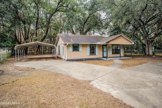 ranch-style home featuring covered porch, fence, concrete driveway, and a detached carport