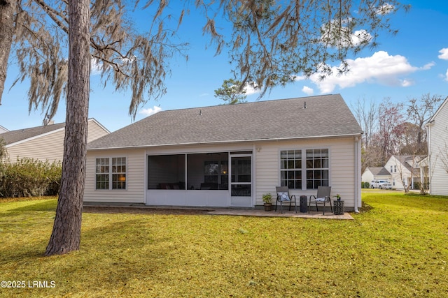 rear view of house featuring a sunroom, a patio area, a yard, and roof with shingles