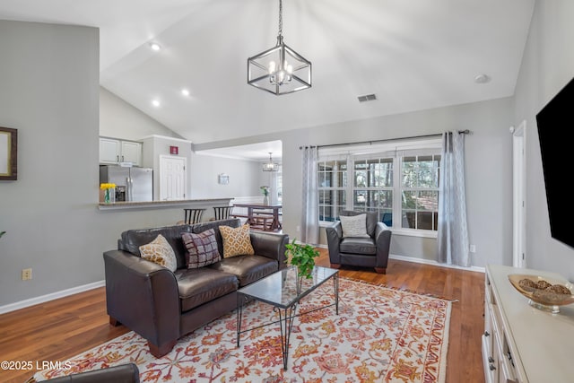 living room with a chandelier, visible vents, and wood finished floors