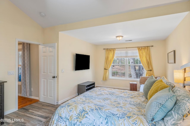 bedroom featuring visible vents, baseboards, vaulted ceiling, and wood finished floors