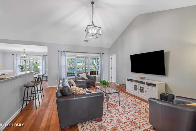 living room with high vaulted ceiling, a notable chandelier, wood finished floors, visible vents, and baseboards