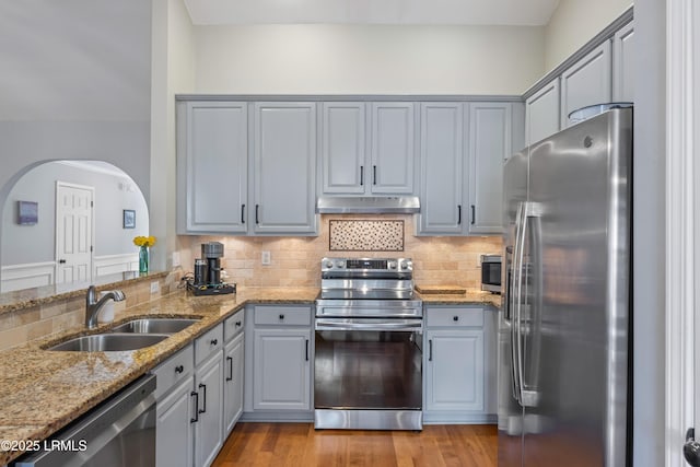 kitchen with gray cabinetry, appliances with stainless steel finishes, a sink, and under cabinet range hood