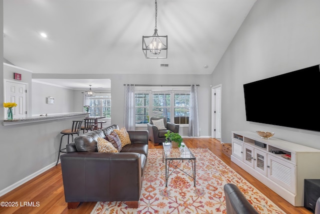 living area with a wealth of natural light, a chandelier, and wood finished floors