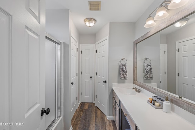 bathroom with vanity, wood finished floors, an enclosed shower, and visible vents