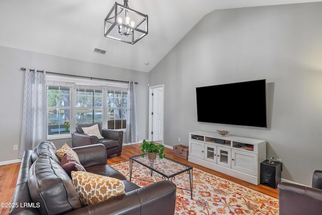 living area with a chandelier, wood finished floors, visible vents, and baseboards