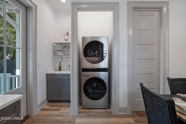 1411 Duke St, Beaufort, SC 29902 - washroom with stacked washer and clothes dryer, light wood finished floors, and a bar