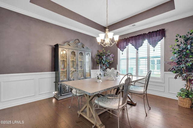 dining space with dark wood-style floors, a wainscoted wall, a decorative wall, and a tray ceiling