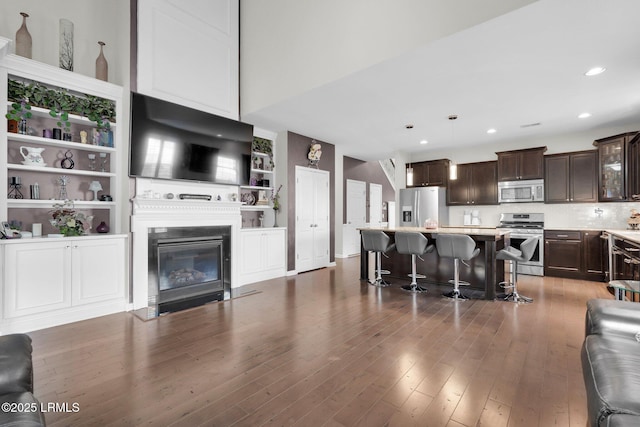living room featuring recessed lighting, wood finished floors, and a glass covered fireplace