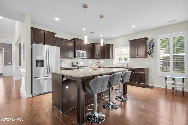 kitchen with visible vents, dark brown cabinets, appliances with stainless steel finishes, and a kitchen island