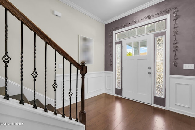 foyer entrance featuring ornamental molding, wainscoting, stairway, and dark wood finished floors
