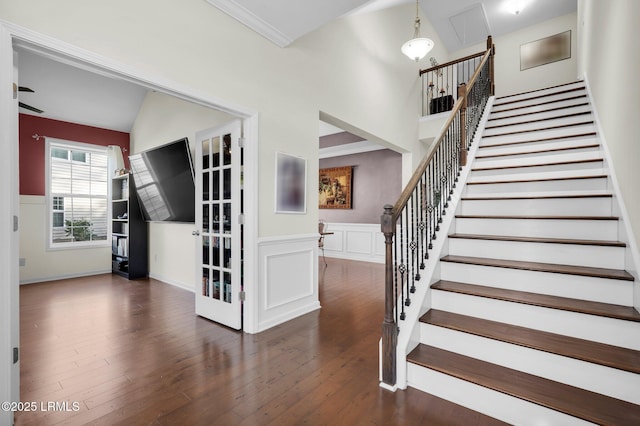 staircase featuring wood finished floors, ornamental molding, and wainscoting