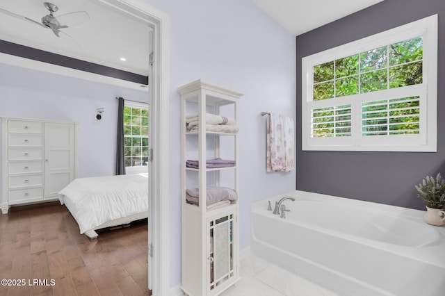 ensuite bathroom featuring ensuite bathroom, baseboards, a bath, wood finished floors, and a ceiling fan