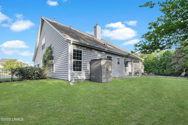 back of property with a chimney, fence, and a yard
