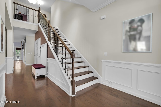 stairs featuring a decorative wall, crown molding, and wood-type flooring