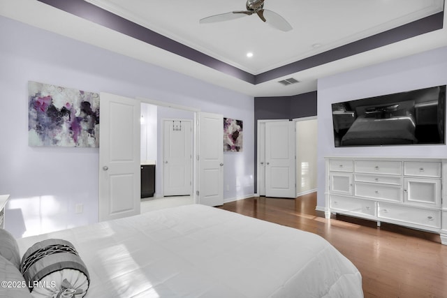 bedroom featuring wood finished floors, ornamental molding, ceiling fan, baseboards, and visible vents