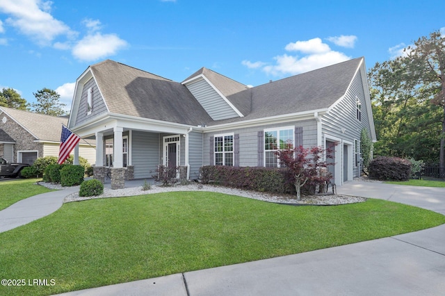 view of front facade with a front lawn, covered porch, a shingled roof, and concrete driveway