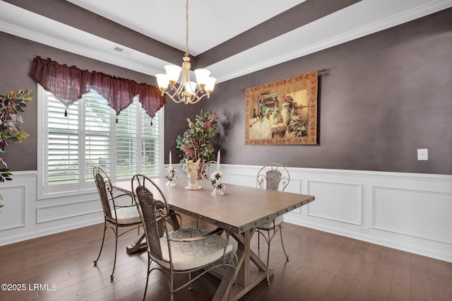 dining room with visible vents, a wainscoted wall, a tray ceiling, wood-type flooring, and an inviting chandelier