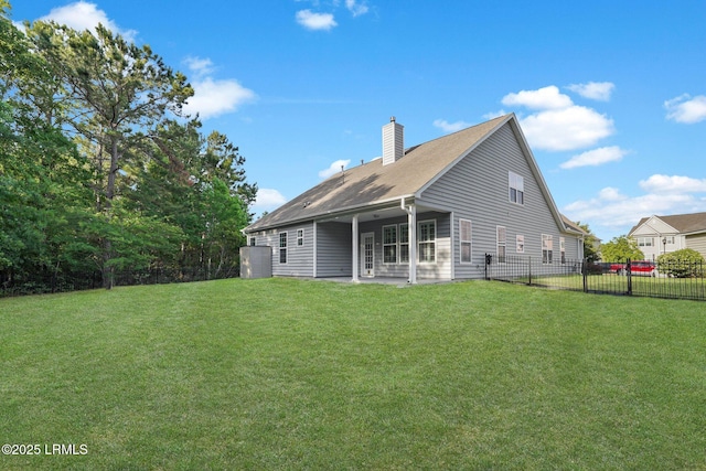 back of property with fence, a chimney, a yard, and a patio area