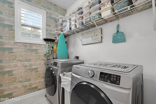 laundry area featuring wooden walls, washer and dryer, laundry area, and baseboards