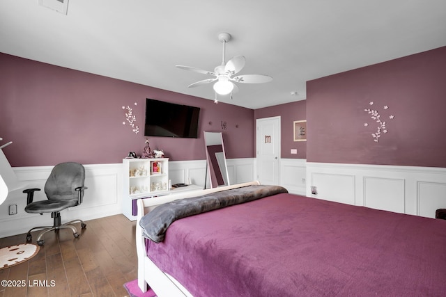 bedroom featuring visible vents, ceiling fan, wood-type flooring, and wainscoting