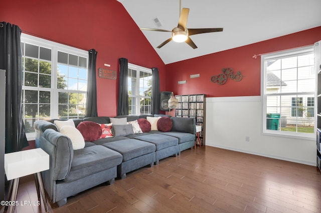 living room with high vaulted ceiling, a ceiling fan, visible vents, baseboards, and wood finished floors