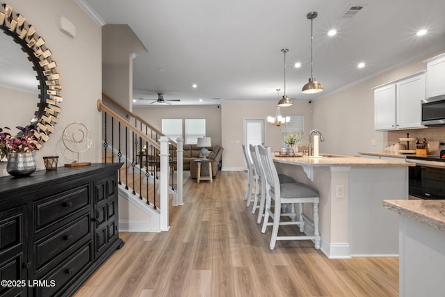 kitchen with crown molding, white cabinetry, appliances with stainless steel finishes, and light wood-type flooring