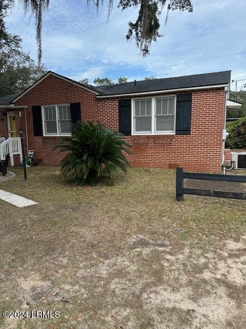 ranch-style home featuring central AC unit and a front lawn