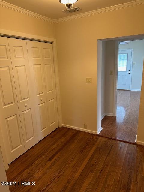 unfurnished bedroom with ornamental molding, dark hardwood / wood-style floors, and a closet