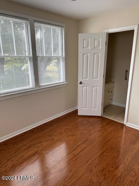 unfurnished bedroom featuring multiple windows and hardwood / wood-style floors