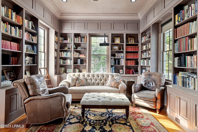 living area with crown molding, light wood-type flooring, and built in shelves