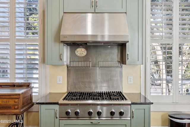 kitchen with a wealth of natural light, stainless steel gas cooktop, dark stone countertops, and range hood