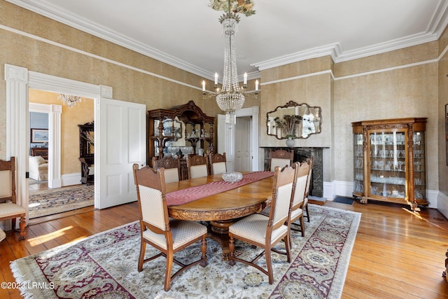 dining space featuring a notable chandelier, crown molding, wood-type flooring, and a fireplace