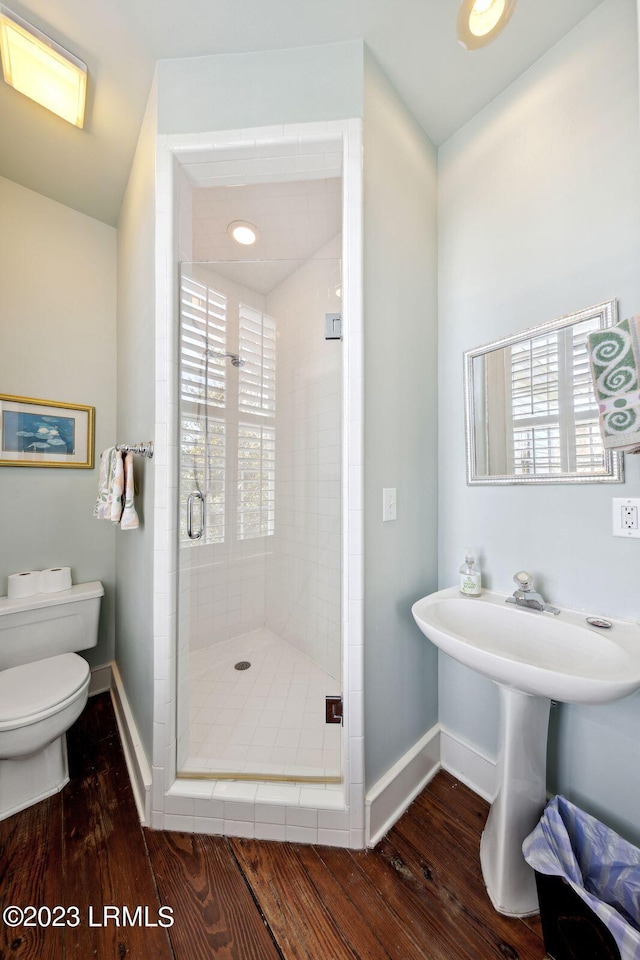 bathroom featuring wood-type flooring, a shower with door, and toilet