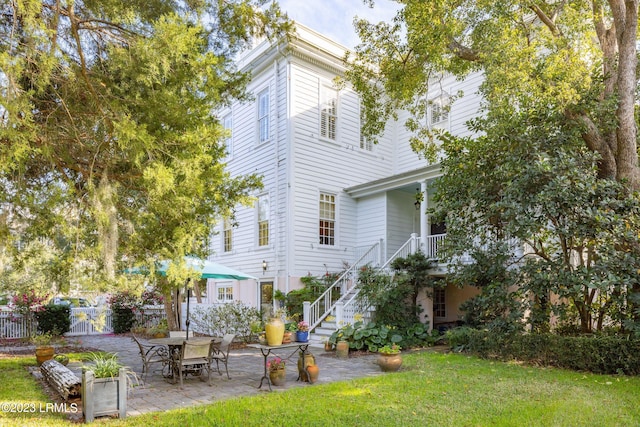 rear view of house with a patio and a lawn