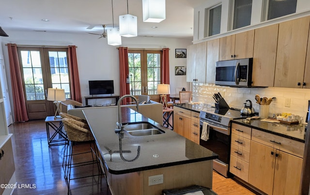 kitchen featuring sink, stainless steel appliances, french doors, and an island with sink